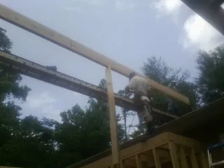 Carpenter setting a ridge beam over a new addition frame — Ice Dam Removal by Roofing Brothers in Sigourney
