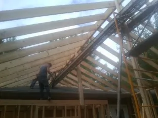Rafters going up over a new addition with a worker on the wall in Sigourney