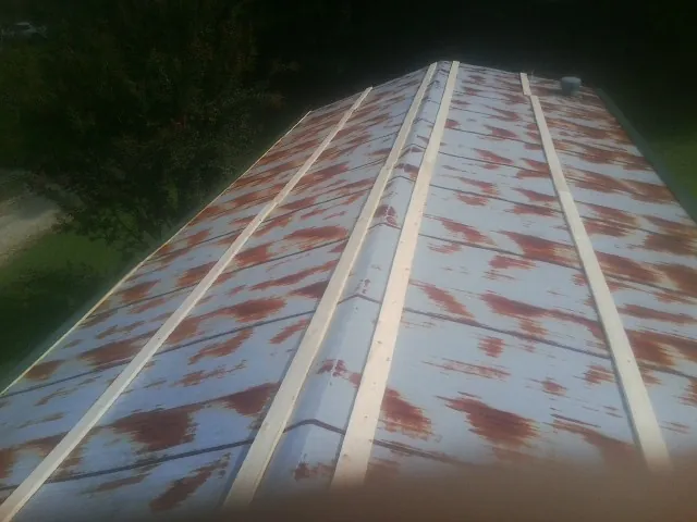 Rusted metal roof panels with new wood purlins before replacement — Storm Damage Roof Repair in Sigourney by Roofing Brothers