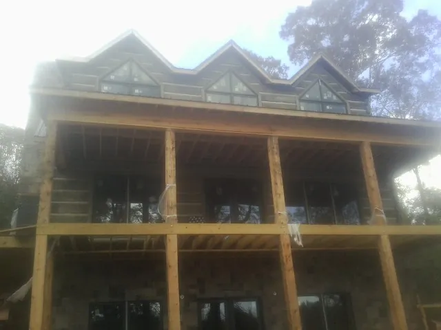 Dormers and porch framing on a large log home under construction — Roof Coating work by our crew in Sigourney