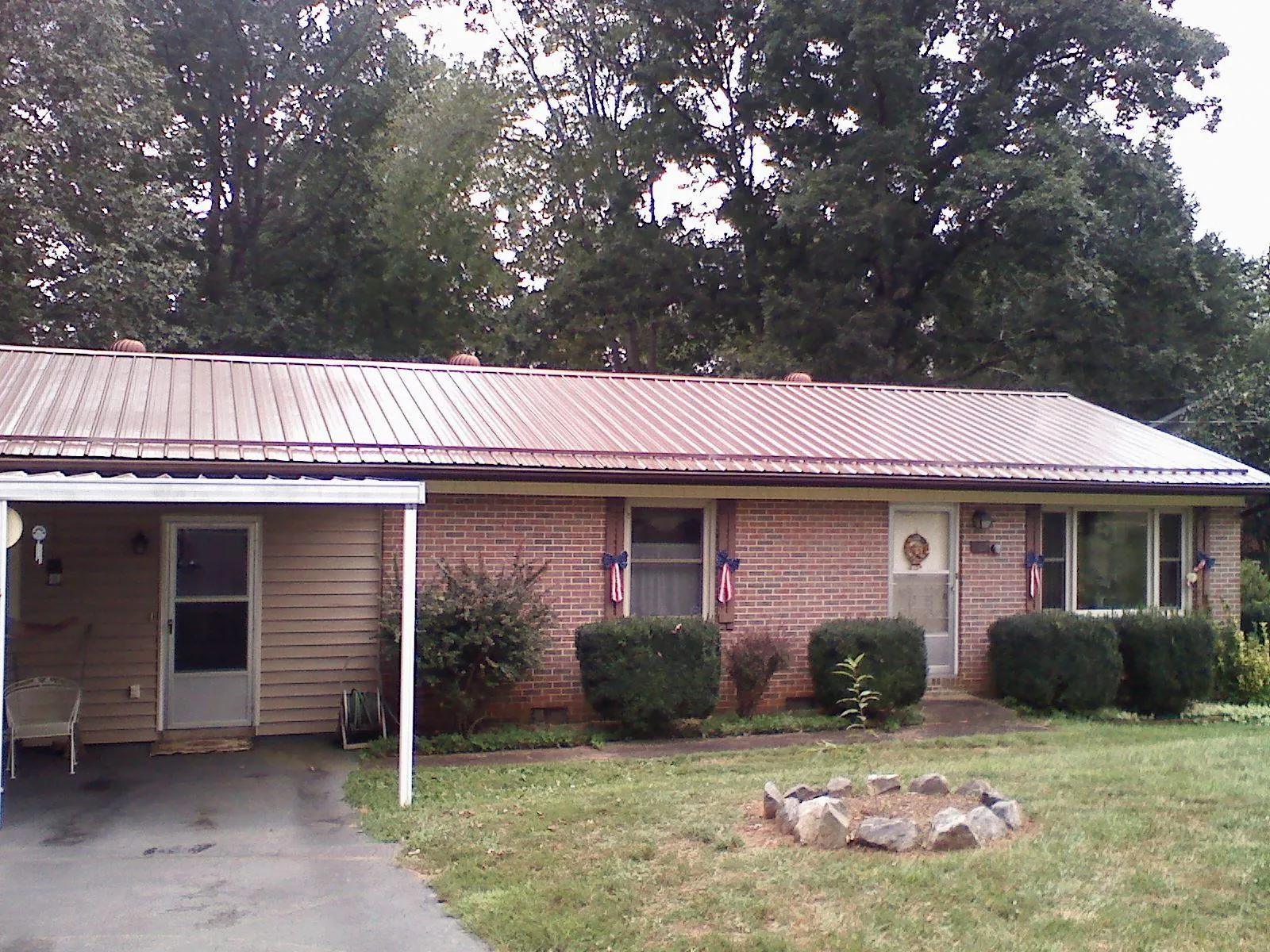 Bronze metal roof and carport on a brick ranch home — Roof Repair work by our crew in Sigourney